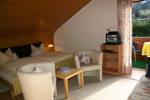 a bedroom with a bed and two chairs and a television at Pension Hoisl in Schönberg