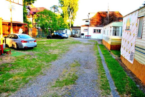 a gravel driveway with cars parked in a yard at SummerCampMielno Domki Holenderskie in Mielno