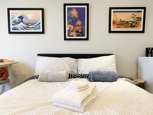 una camera con un letto con tre immagini appese al muro di CozyTomari a Londra