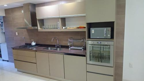 una cocina con fregadero y microondas en departamento 2 dormitorios Cinzano planta baja, en San Juan