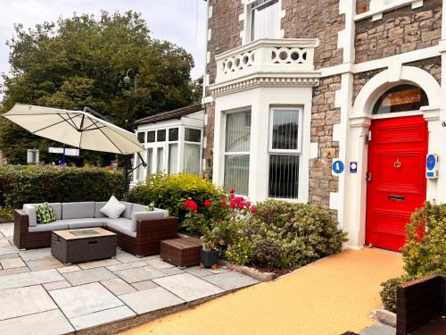a red door on a house with a couch and an umbrella at The Grove in Weston-super-Mare