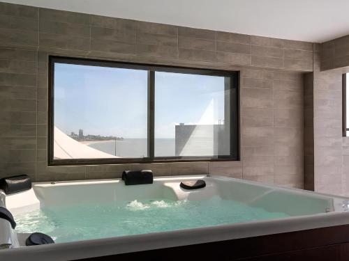 uma banheira na casa de banho com uma grande janela em Apart-hotel Beira-Mar em Manaíra em João Pessoa