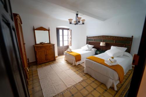 een slaapkamer met 2 bedden en een spiegel bij La bodega D'leti in Jarandilla de la Vera
