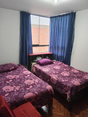 a bedroom with two beds and a window with blue curtains at Yanahuara apartaments in Arequipa