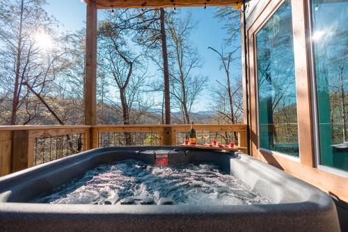 uma banheira de hidromassagem numa casa com janela em Romantic Cabin Retreat By Ghosal Luxury Lodging em Gatlinburg