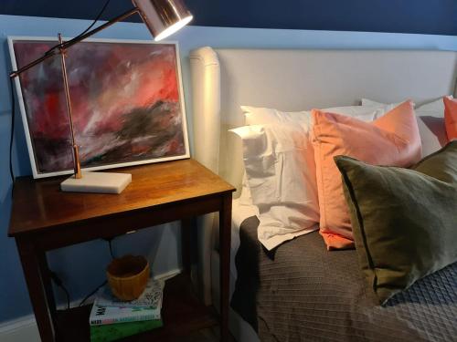a painting on a table next to a bed with pillows at Beach Hideaway in Shanklin