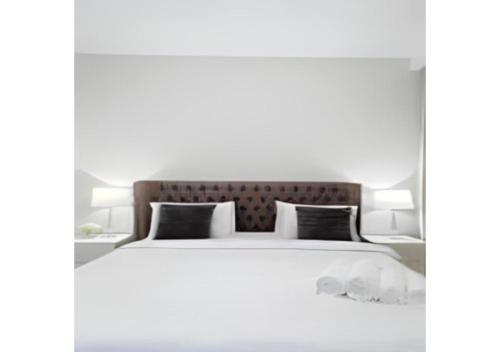 杜拜的住宿－Key View - Welcome Residency，卧室配有一张带黑色枕头的大型白色床。