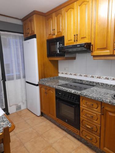 uma cozinha com armários de madeira e um forno de fogão preto em Carmina fondon 3 em Cangas de Onís