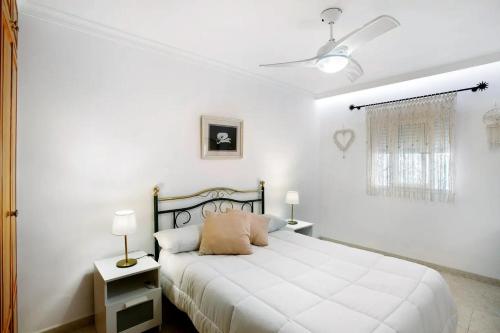 ein weißes Schlafzimmer mit einem Bett und zwei Lampen in der Unterkunft Apartamento Ca' Toba in Mogán