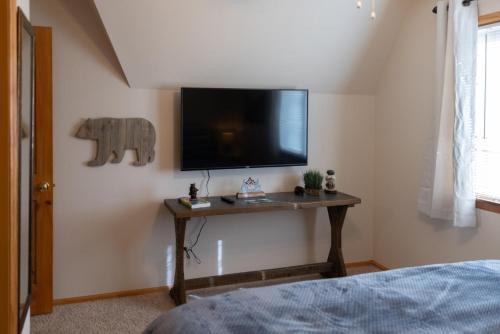 a room with a tv on a wall with a table at Lazy Bear Lodge in Florissant with Mountain Views! in Florissant