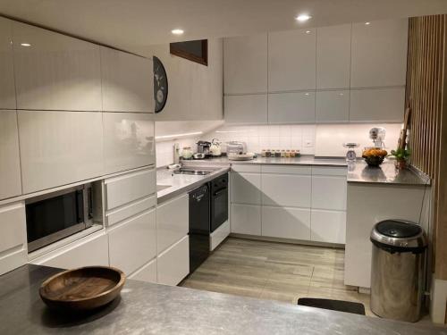 une grande cuisine avec des placards blancs et un comptoir dans l'établissement Péniche au calme sur la Seine, à Rueil-Malmaison