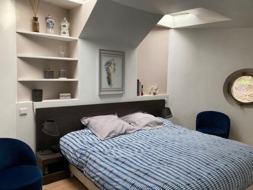 - une chambre avec un lit et deux chaises bleues dans l'établissement Péniche au calme sur la Seine, à Rueil-Malmaison