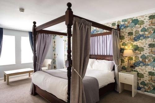 um quarto com uma cama de dossel e papel de parede floral em Moor Hall Hotel, BW Premier Collection em Sutton Coldfield