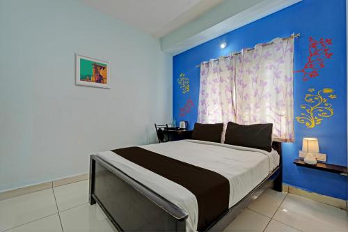 a bedroom with a bed with a blue wall at OYO Flagship 81266 Slv Hotel in Bangalore