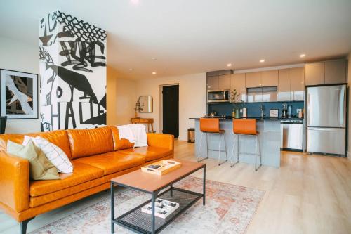 een woonkamer met een oranje bank en een keuken bij NEW Stylish 2BR Condo with Views in North End in Halifax