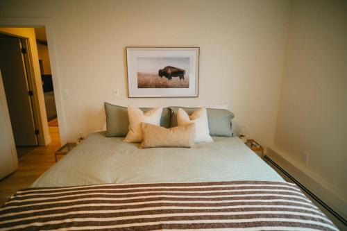 a bedroom with a bed with pillows and a picture of a cow at Chic Cozy Retreat - 2BR - Stunning North End Views in Halifax