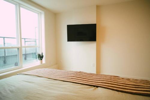 a bedroom with a bed with a television on the wall at Chic Cozy Retreat - 2BR - Stunning North End Views in Halifax