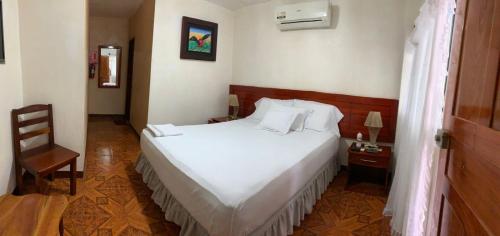 1 dormitorio con 1 cama blanca y 1 silla en Casa de Huespedes Milena, en Puerto Baquerizo Moreno