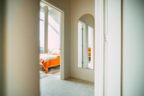a bedroom with an orange bed and a mirror at NEW Luxury 2BR Penthouse Apt In Central Halifax in Halifax