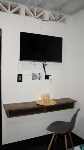 a tv on a wall with a table and a chair at Hostal Queens Deluxe in Florencia