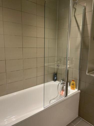 a shower with a glass door next to a tub at West Heights SE in Croydon