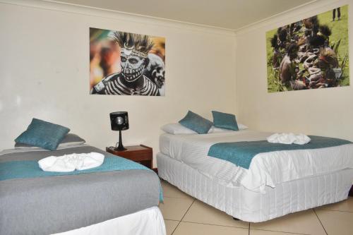 a bedroom with two beds and a picture on the wall at Pacific Gardens Hotel in Goroka