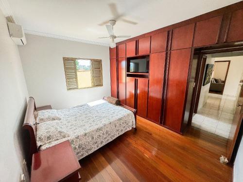 um quarto com uma cama e armários de madeira em Casa Completa com Churrasqueira em Patos de Minas em Patos de Minas