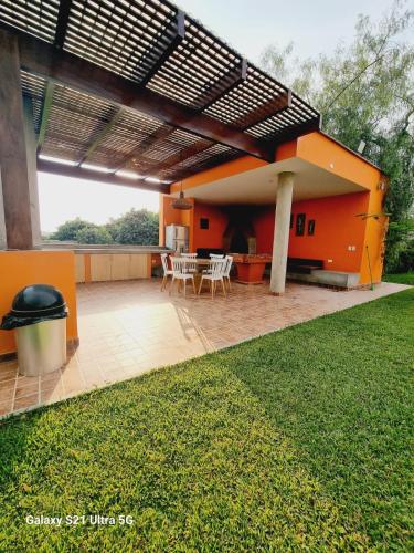 Casa de color naranja con patio con mesa y sillas en CASA LINDA PACHACAMAC, en Pachacámac