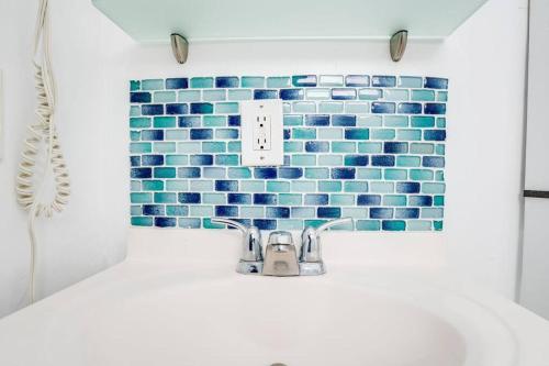 La salle de bains est pourvue d'un lavabo et d'un mur en carrelage bleu. dans l'établissement Amazing apartment in Miami Beach, à Miami Beach