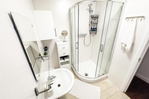 a white bathroom with a shower and a sink at O'Connell Place in Dublin