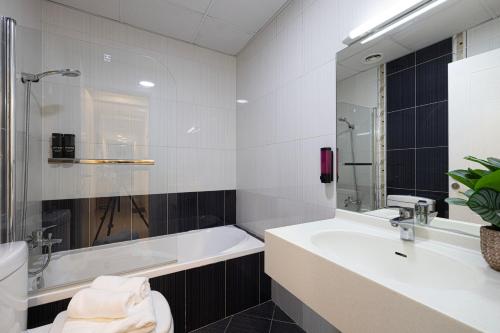 ein weißes Badezimmer mit einer Badewanne und einem Waschbecken in der Unterkunft Stylish 3 bedrooms Boho-Style Home in Dubai