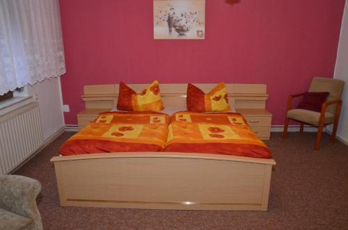 1 Schlafzimmer mit 2 Betten mit orangefarbenen und gelben Kissen in der Unterkunft Ferienwohnung Wunderlich in Krausnick