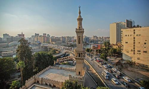 a clock tower in the middle of a city with traffic at Zamalek X Hostel-Nile view in Cairo