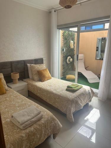 a bedroom with two beds and a sliding glass door at Appartement Plage près d’Agadir in Aourir