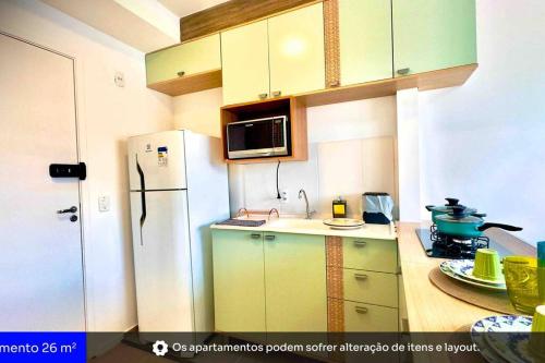 cocina con armarios verdes y nevera blanca en 701- Rentaqui Comfort Liberdade Green, en São Paulo