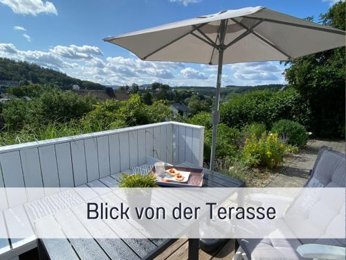 a picnic table with an umbrella and a bowl of food at Ferienhaus Dackelglück in Schmallenberg