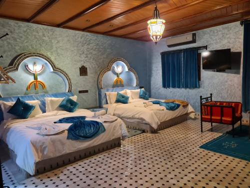 a bedroom with two beds and a tv in it at Kasbah Yasmina Hotel in Lac Yasmins