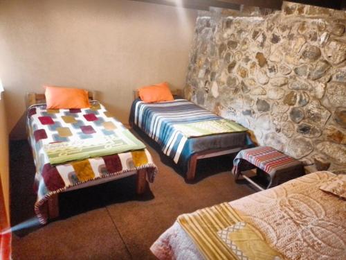 a room with two beds and a stone wall at HOSTEL SAMANA WASI CHAULLAY in Cusco