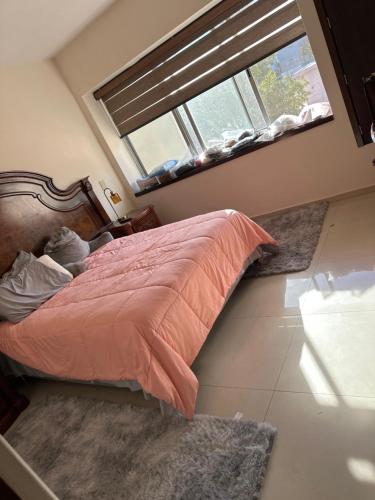 a bedroom with a bed with an orange comforter and a window at Av de las rosas in Guadalajara