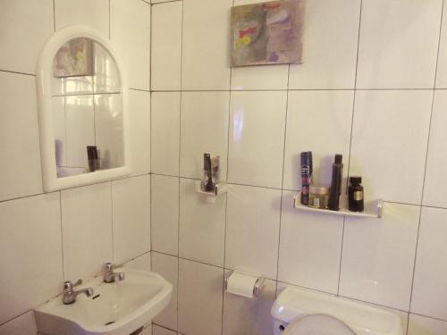 a white tiled bathroom with a sink and a toilet at Templar's court in Port Harcourt