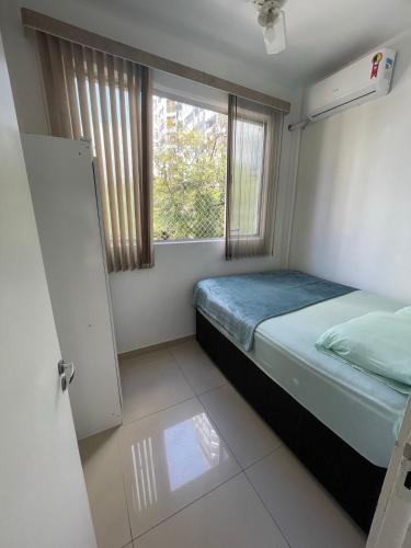 een kleine slaapkamer met een bed en een raam bij Aconchegante apto de 2 quartos a passos da praia. in Balneário Camboriú