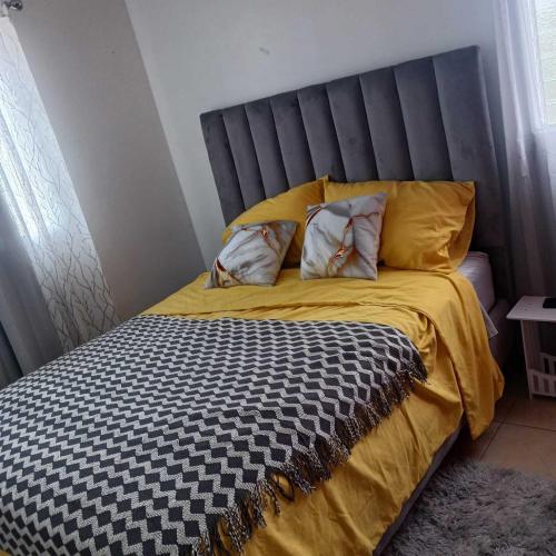 a bed with a black and yellow comforter and two pillows at Ocean Breeze Apartment in La Romana in La Romana