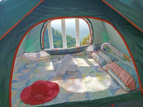 a tent with a bed with a hat and pillows at Cabin de Paulin 2 in Tagaytay