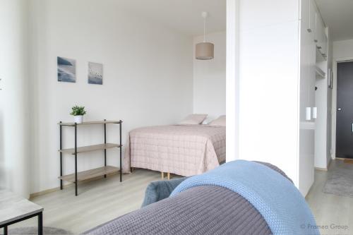 a white bedroom with a bed and a table at City Apartment Pankkitalo in Kuopio
