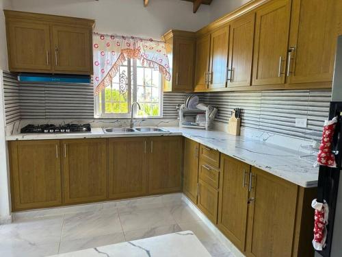 a kitchen with wooden cabinets and a sink and a window at Richie’s House En Licey Al Medio in Santiago de los Caballeros