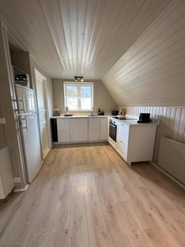a large kitchen with white cabinets and a large window at Cabin in Lava Village with hot tub in Selfoss