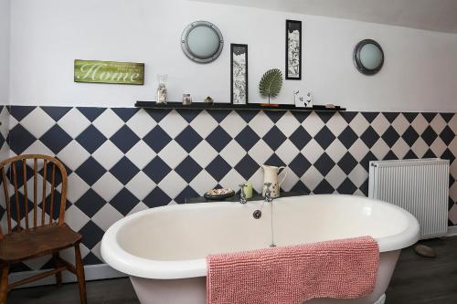 a bath tub in a bathroom with black and white tiles at Beautiful Victorian home with private pet-friendly garden sleeps 6 in Holyhead