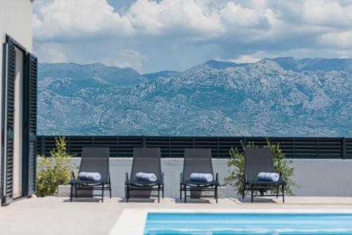 - un groupe de chaises assises à côté de la piscine dans l'établissement Designer Villa Neva With Magic Velebit View, à Ražanac