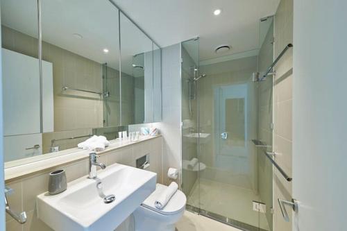 a bathroom with a toilet and a sink and a shower at High-Rise on Collins with Free Parking, Pool, Gym in Melbourne