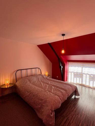 une chambre avec un lit et un mur rouge dans l'établissement GITES au calme, à Soudan